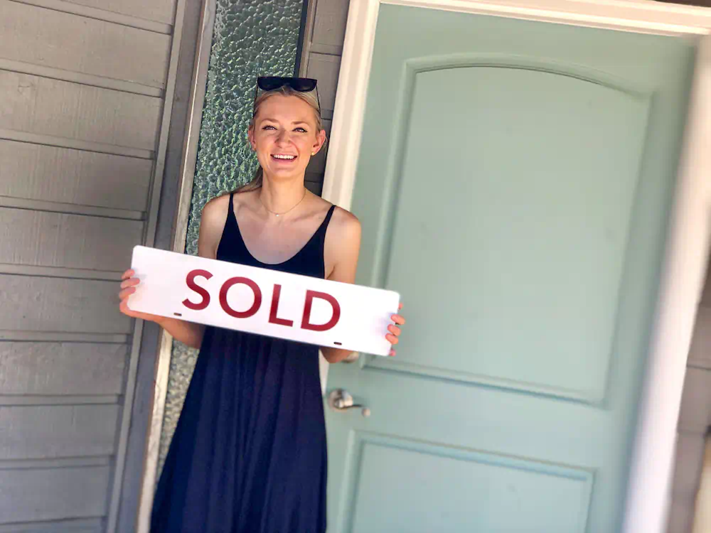 Buyer celebrating with a sold sign in front of her beautiful home in the North Boise Foothills.