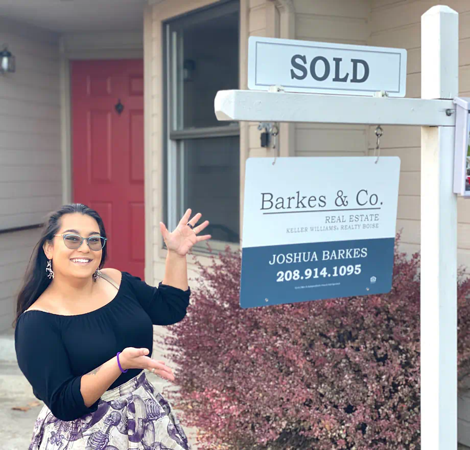 Excited first-time seller standing next to her sold sign in front of her West Boise townhome.