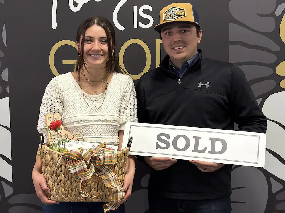 Happy clients with a sold sign who successfully relocated to the Boise area from out-of-state.